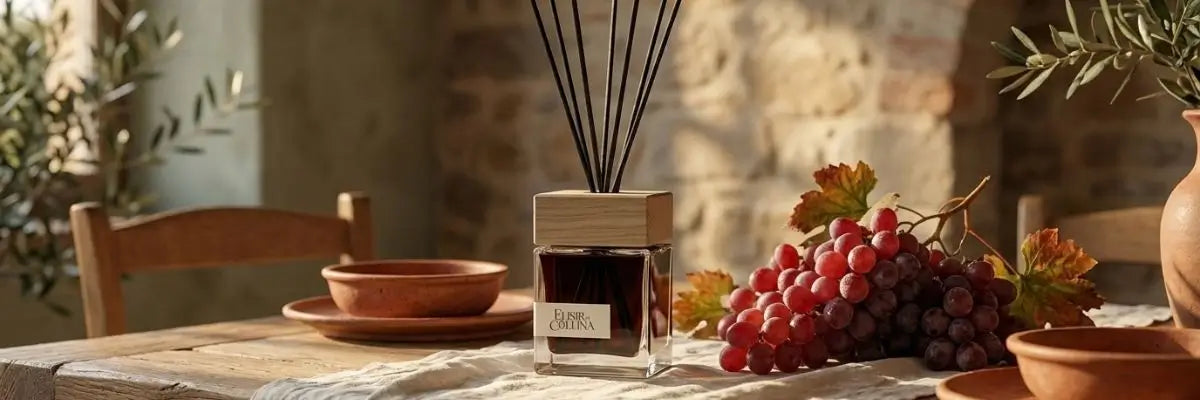 Profumatore ambiente alla fragranza Uva Rossa Elisir di Collina su tavolo in legno e atmosfera da vendemmia.