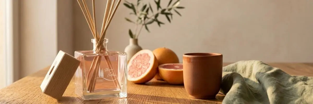 Profumo per la casa Elisir di Collina su un tavolo in legno illuminato dalla calda luce dorata del pomeriggio.