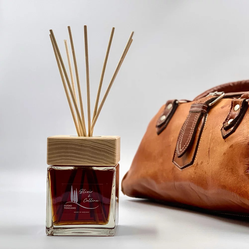 Profumatore d’ambiente Cuoio Toscano con flacone ambrato e accessorio in pelle fiorentina sullo sfondo